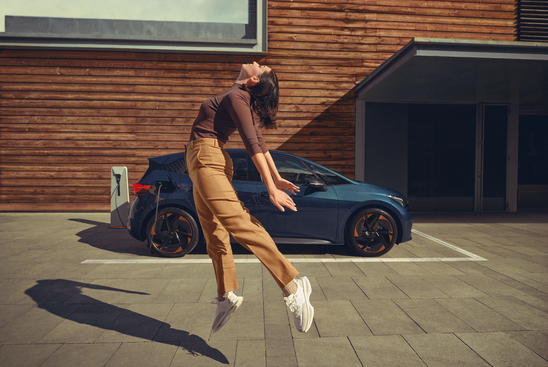 Woman posing while a CUPRA Born Aurora Blue colour charging