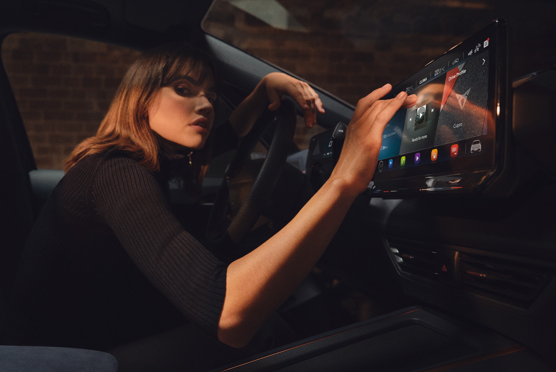 Woman inside a CUPRA Born using the dashboard and infotainment screen