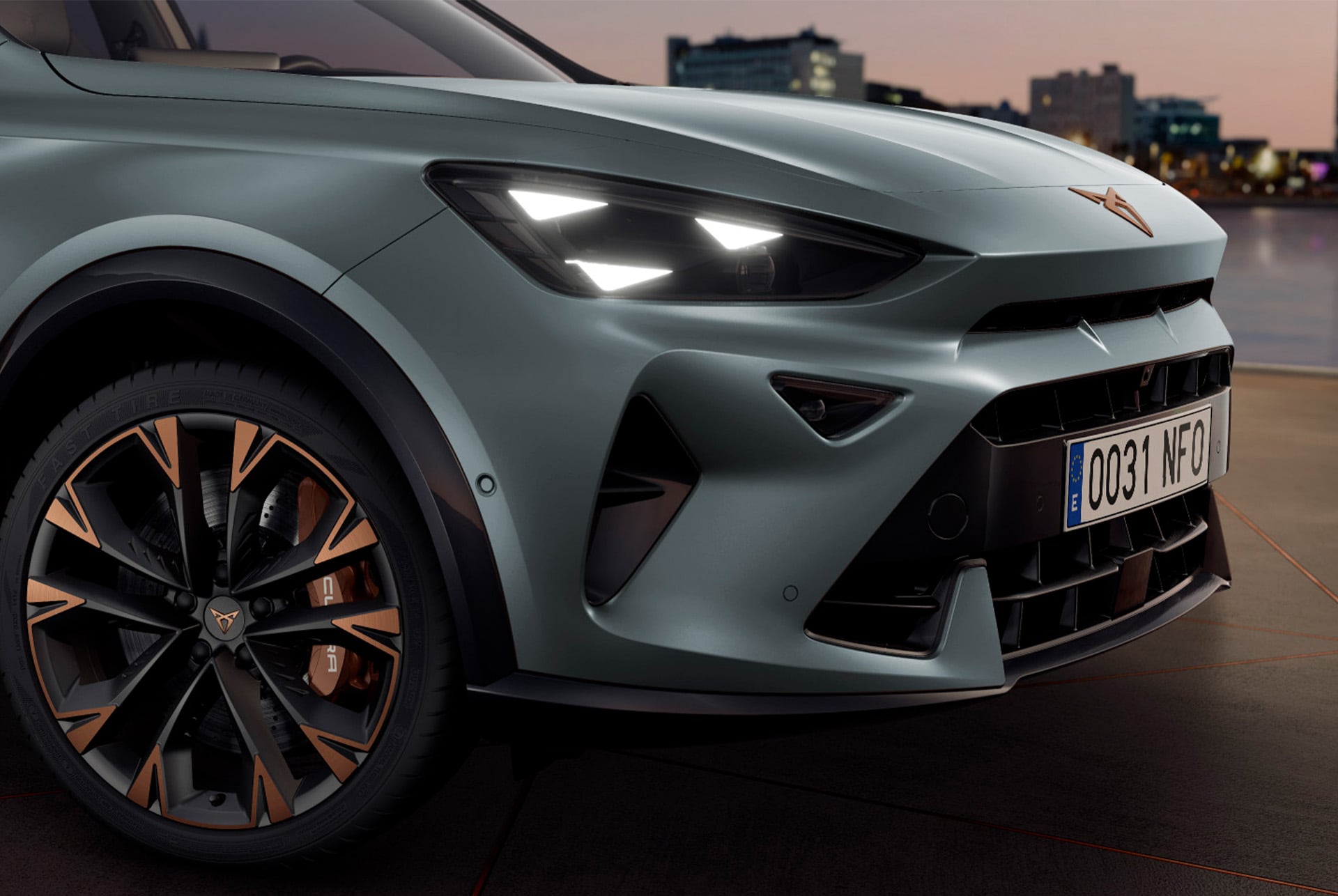 Close-up of the front of the CUPRA Formentor showing the headlights with smart light technology from the Pure Performance pack, parked against an urban background at sunset.