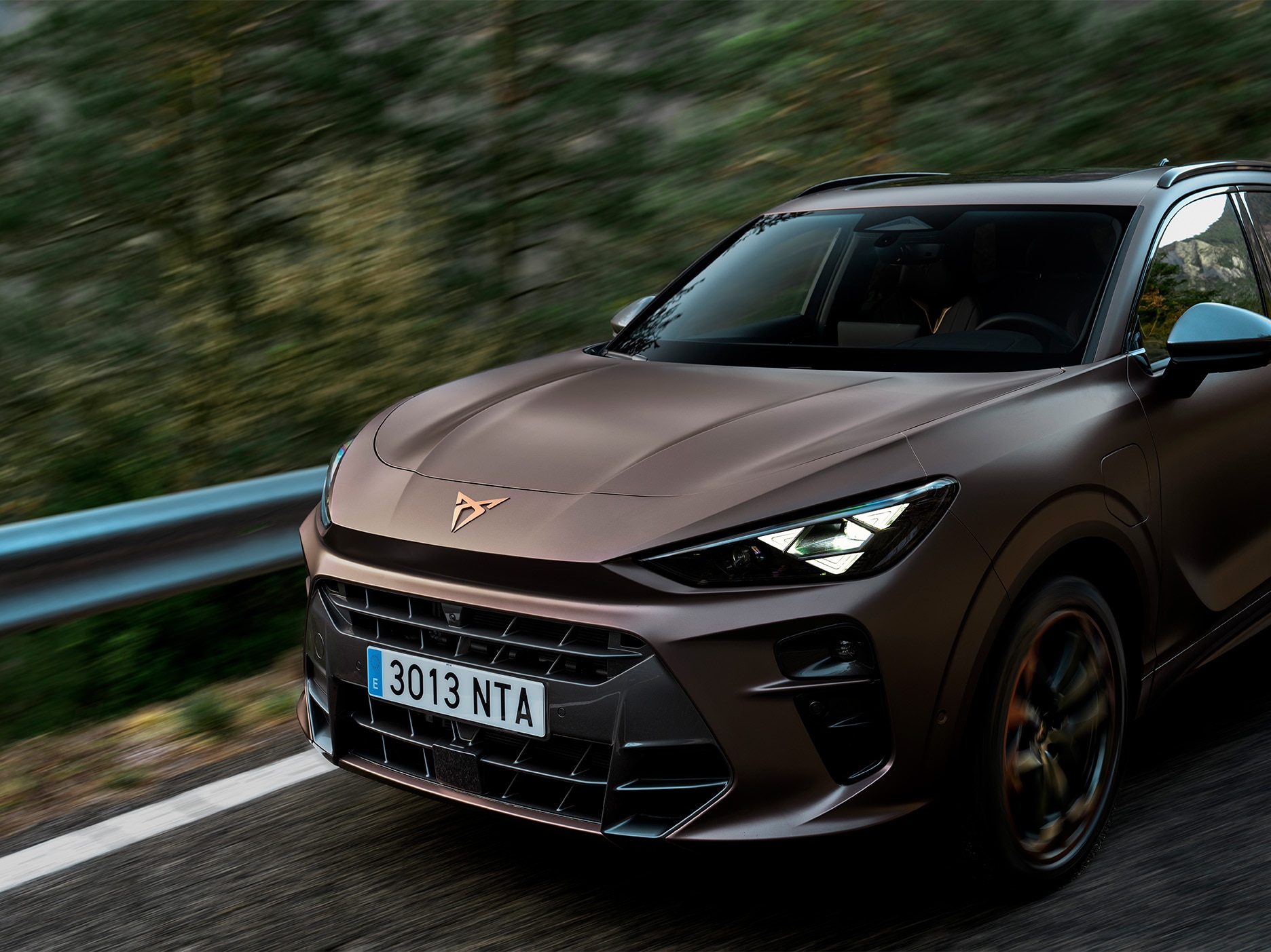Side hero shot of the CUPRA Terramar riding on a road. The image highlights the shark-nose inspired front that adds character to the car.