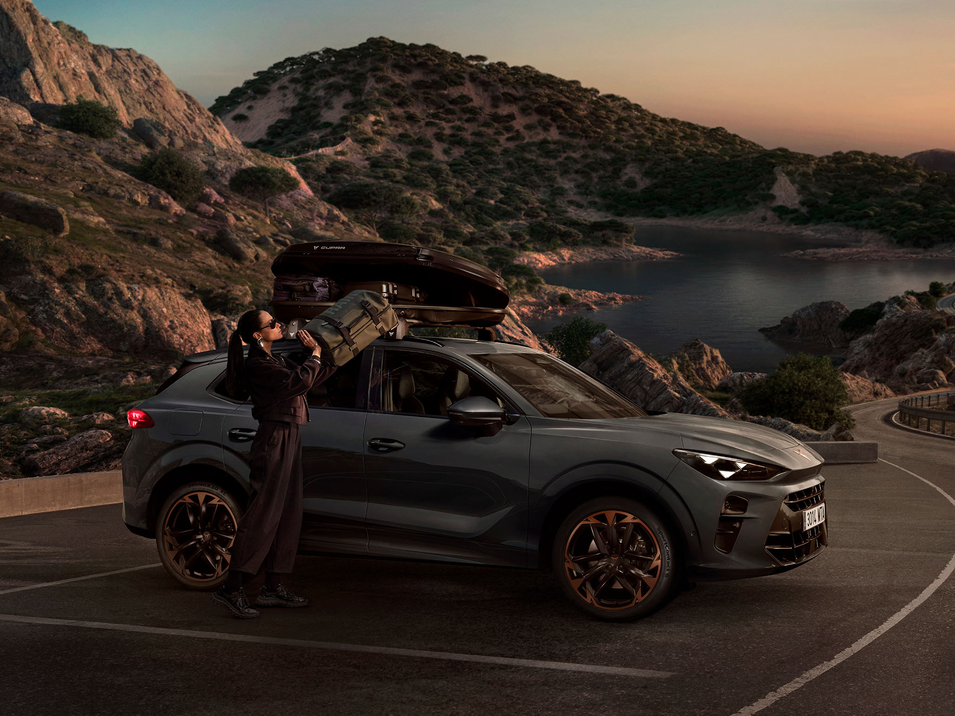 CUPRA Terramar parked in a mountain setting with a woman using the roof rack from the accessories range.