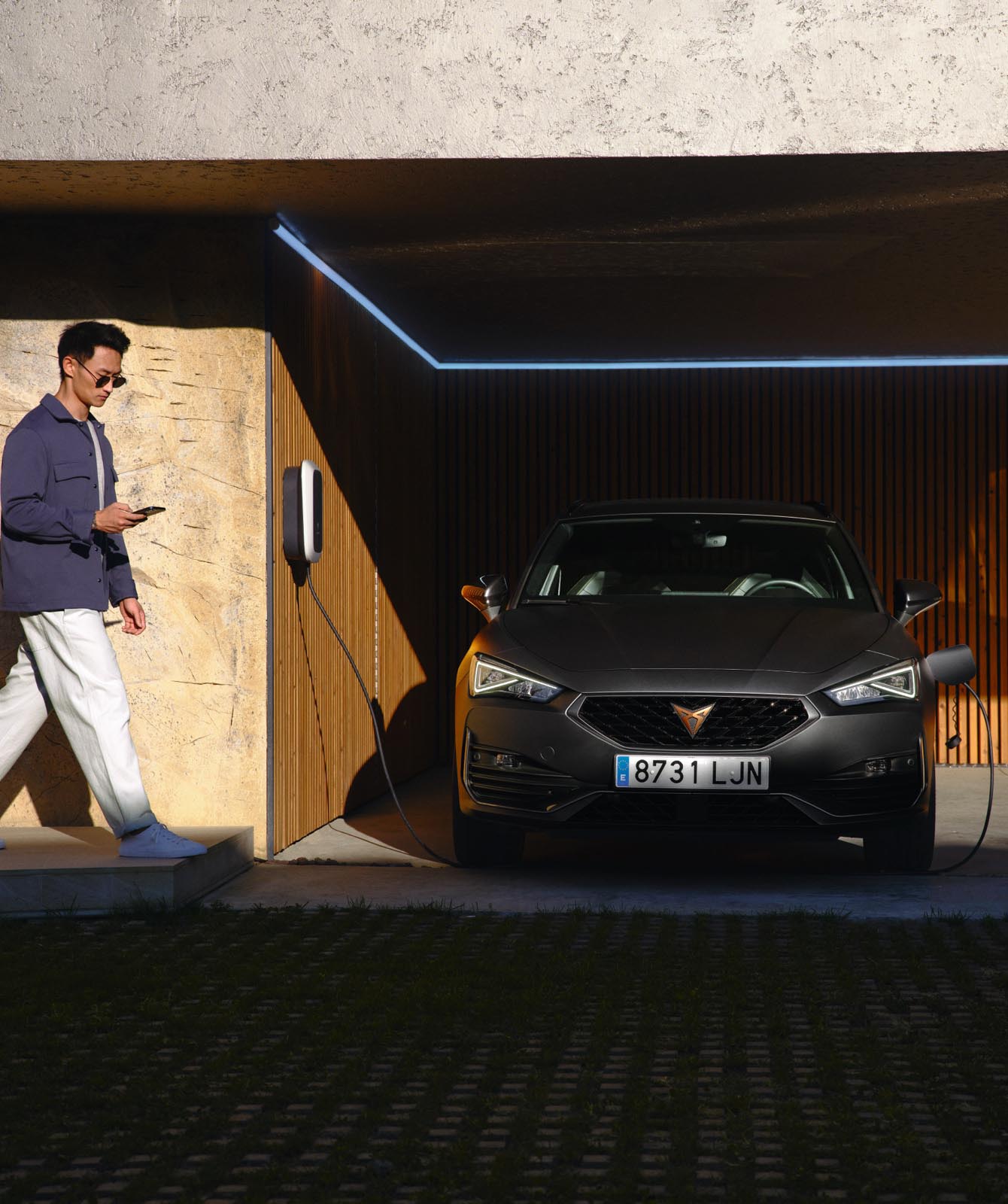 man-walking-in-front-of-cupra-leon-pluged-in